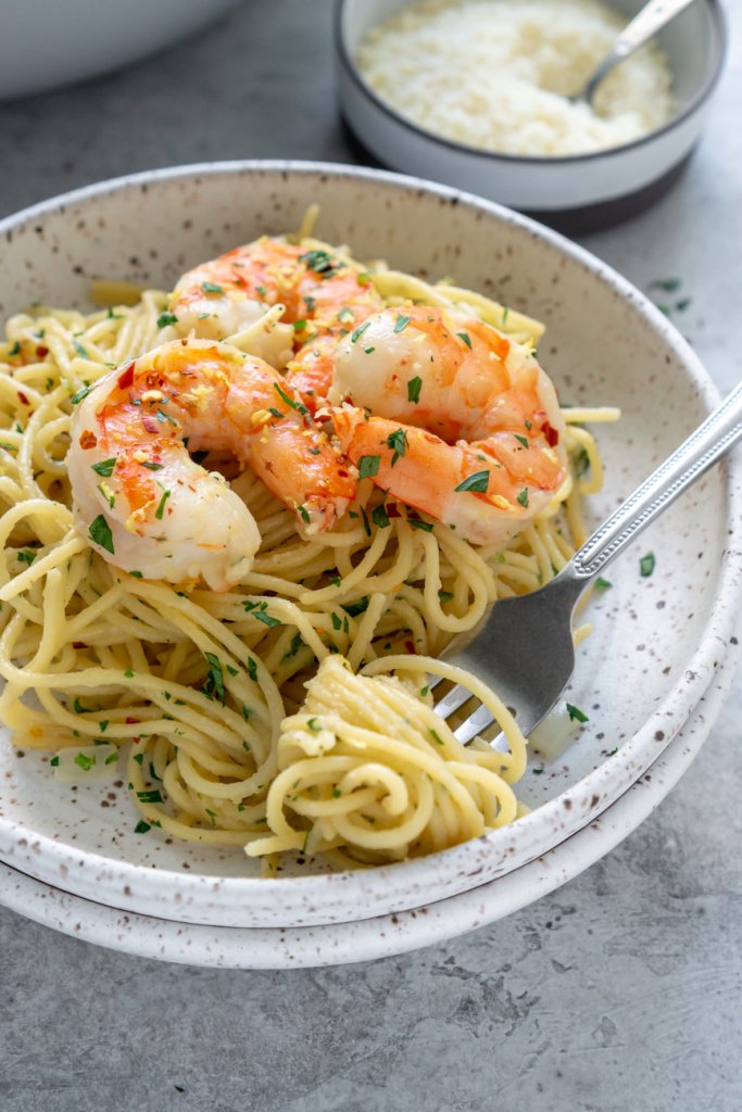 garlic shrimp spaghetti in a white bowl with a fork