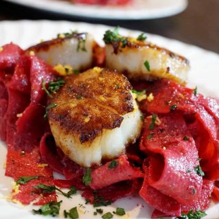 beet pappardelle with scallops on a white plate