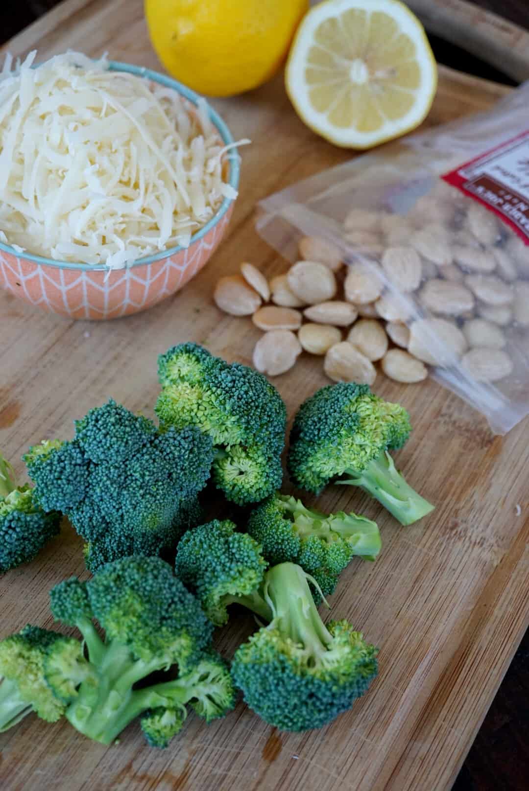 Broccoli, cheese, lemon, and almonds on a cutting board