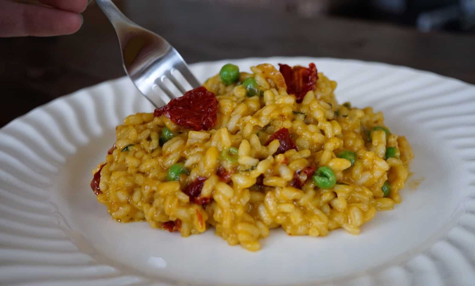 sun dried tomato risotto on a plate with a fork