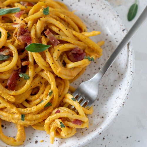 pumpkin pasta on a white plate with a silver fork