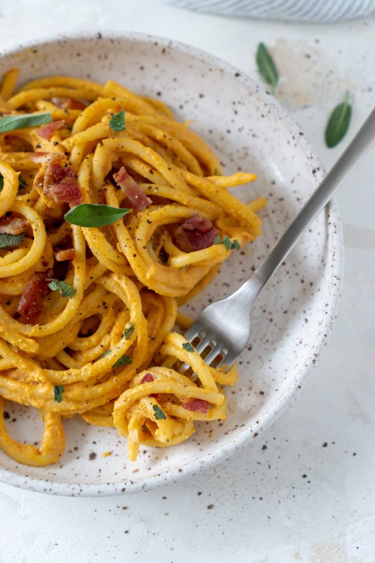 pumpkin pasta on a white plate with a silver fork