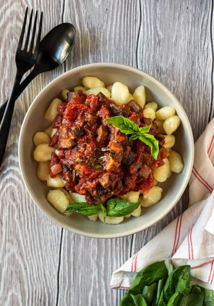 mushroom bolognese sauce in a bowl with gnocchi and a black fork