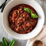 mushroom bolognese sauce in a large white bowl and fresh basil