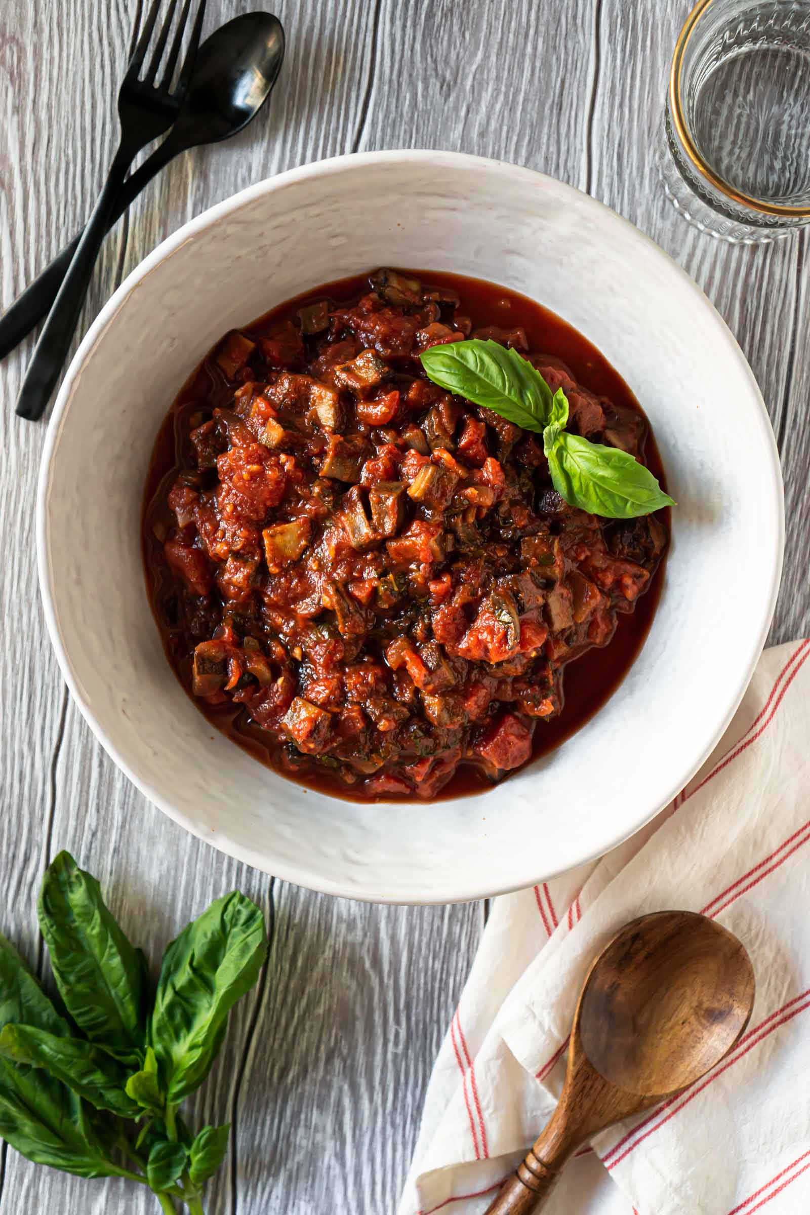 mushroom bolognese sauce in a large white bowl and fresh basil