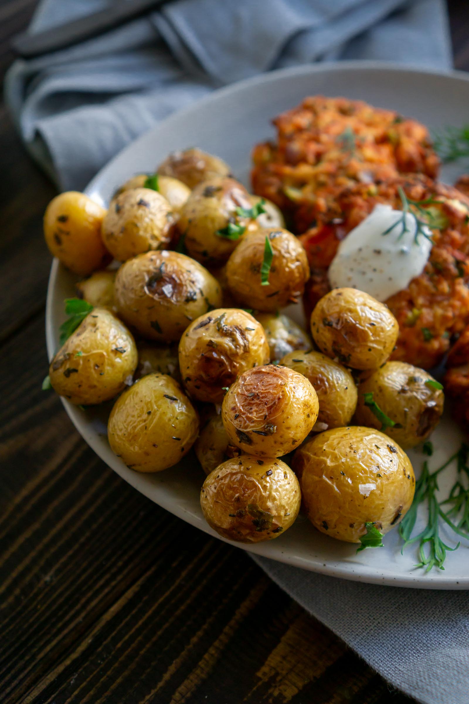Roasted mini potatoes on a plate with salmon cakes.