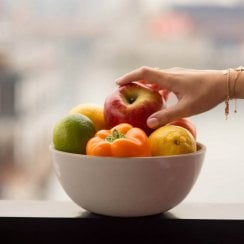 hand reaching into a bowl of fruit
