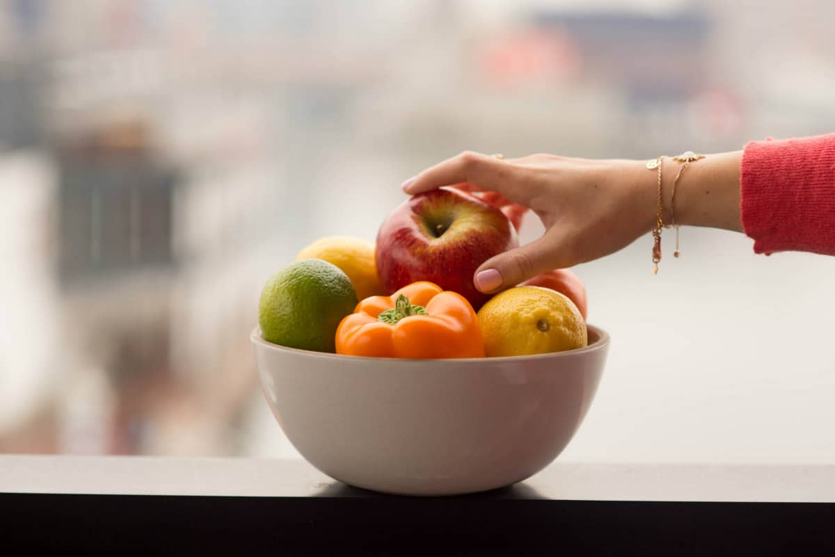 hand reaching into a bowl of fruit