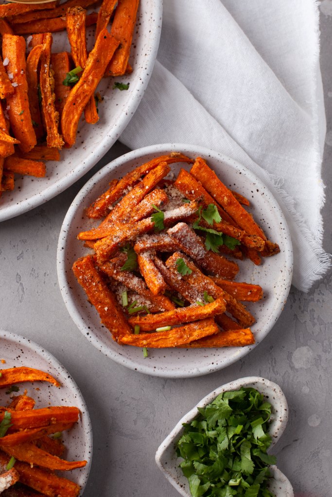 three plates with sweet potato fries and parsley on the side