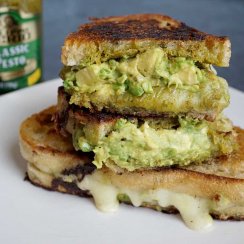 pesto grilled cheese cut in half and stacked with pesto jar