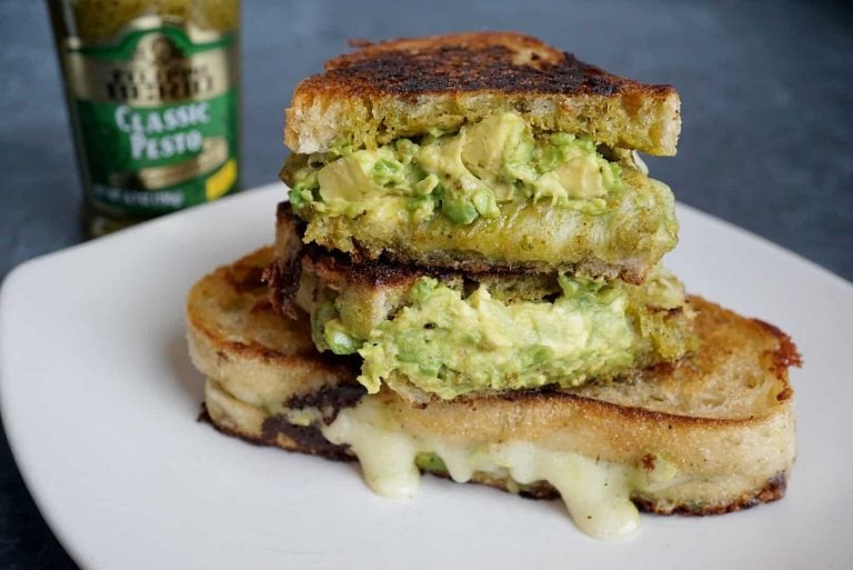 pesto grilled cheese cut in half and stacked with pesto jar