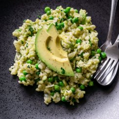 avocado risotto on a black plate with a silver fork and spoon