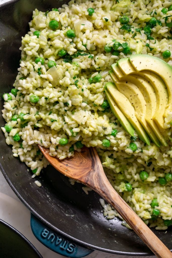avocado risotto in a skillet with a wooden spoon