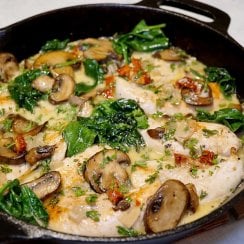 Chicken, spinach, mushrooms, and cream sauce in a cast iron pan