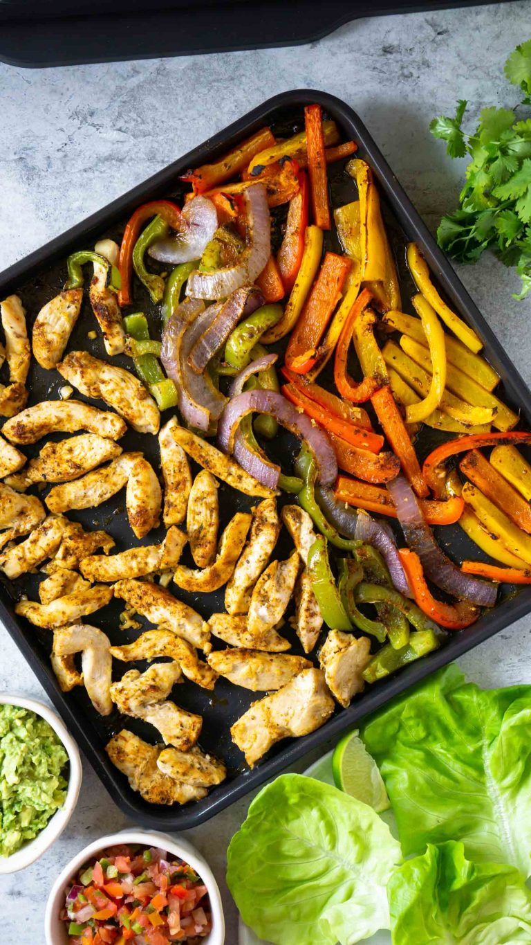 whole30 sheet pan fajitas on a baking sheet with salsa and guacamole