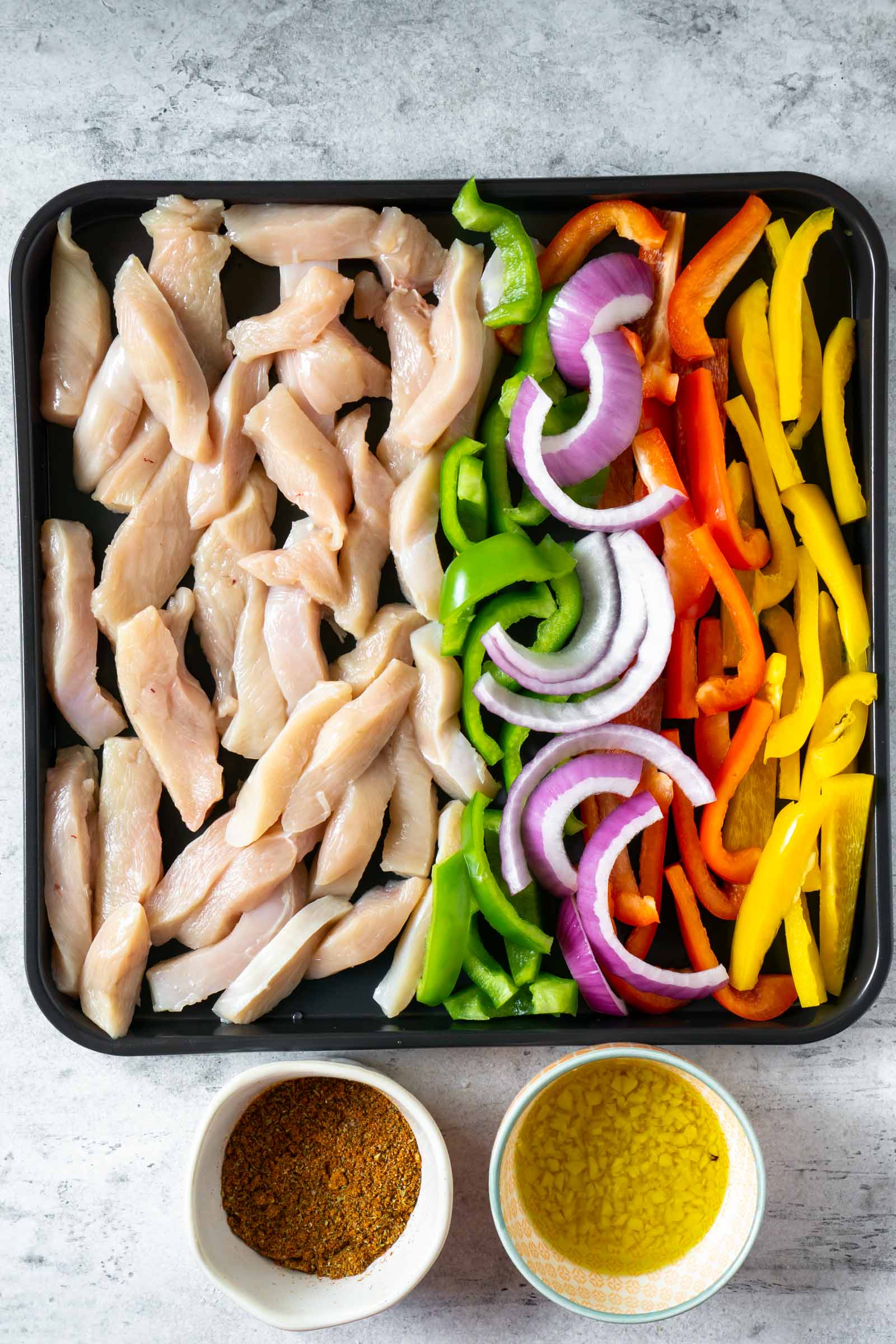 chicken and vegetables on a sheet pan with two small bowls