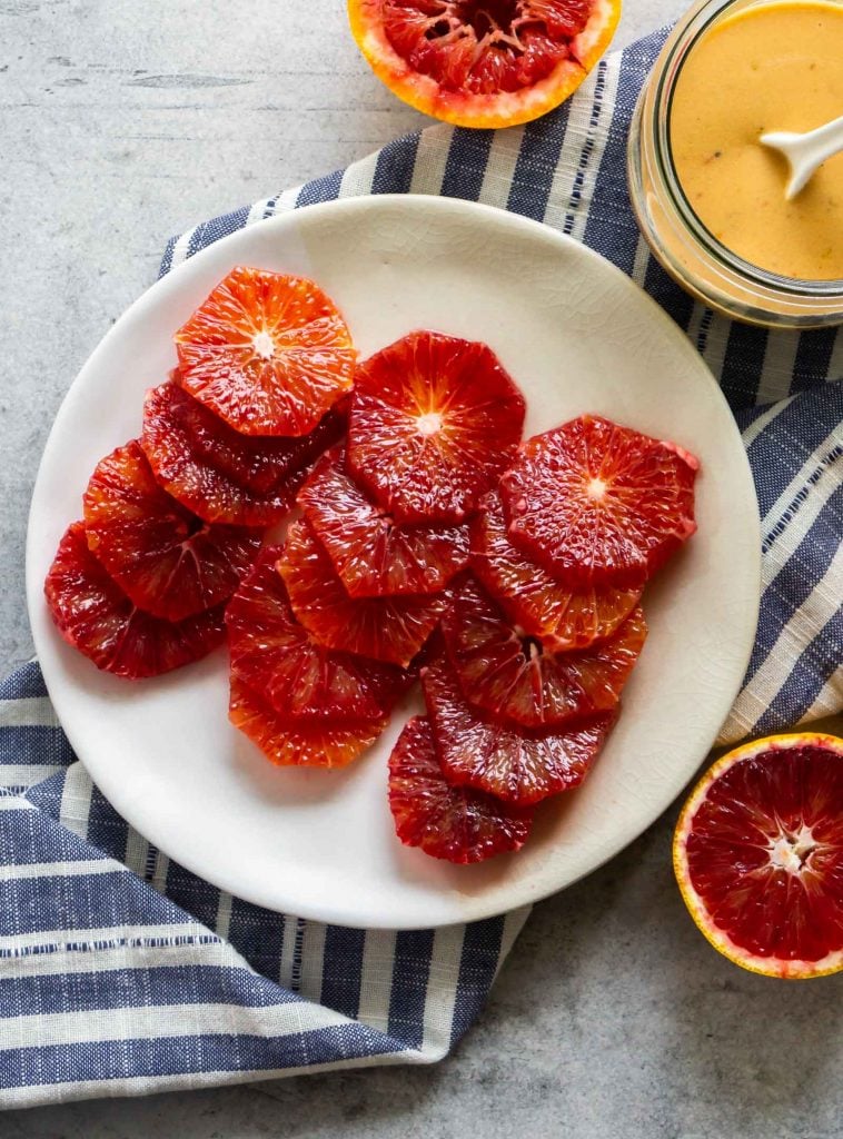 sliced blood oranges on a plate with a blue striped napkin