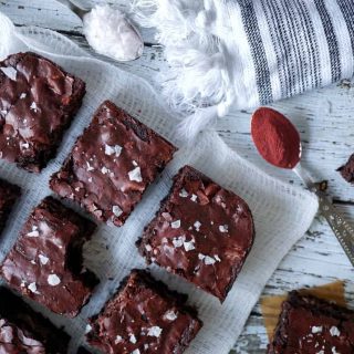 Brownies on a cheese cloth with two spoons of beetroot powder and flaky salt