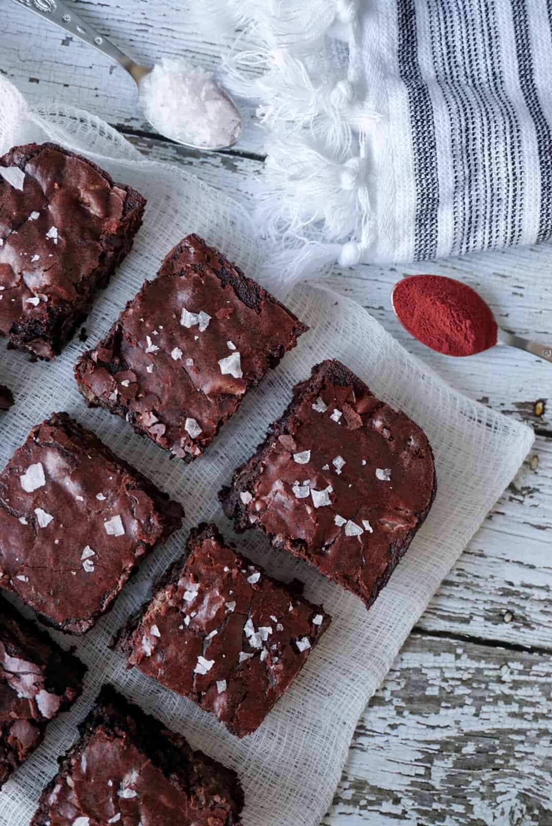 Brownies on a cheese cloth with two spoons of flaky salt and beetroot powder