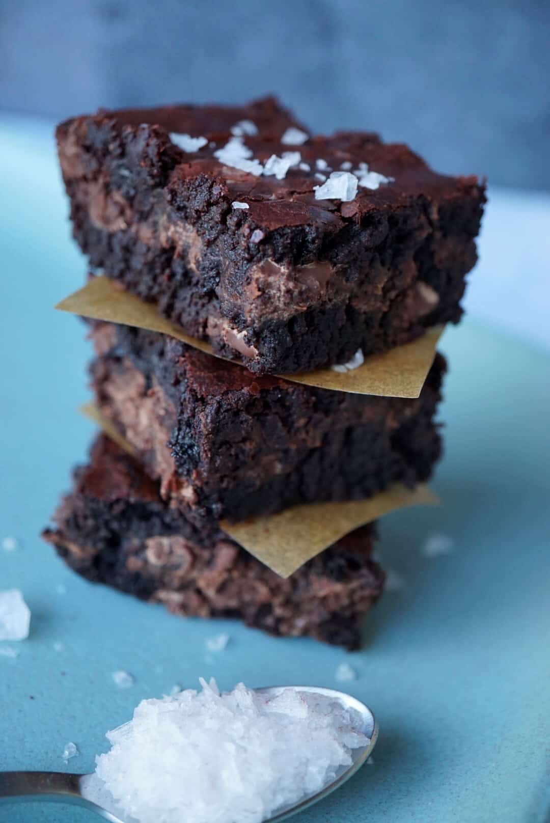 Three brownies stacked with a spoon of flaky salt