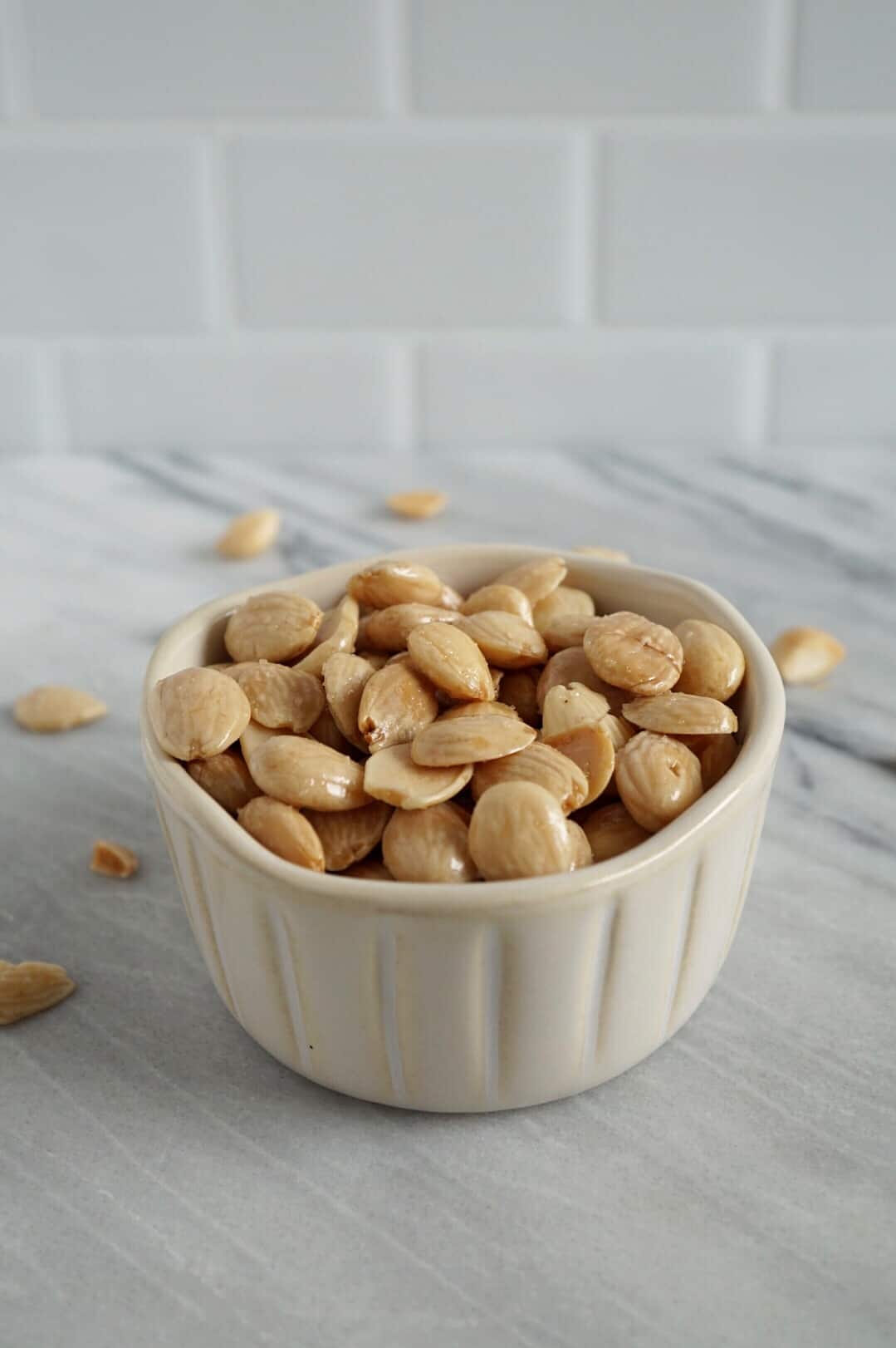 Marcona almonds in a white bowl on marble counter