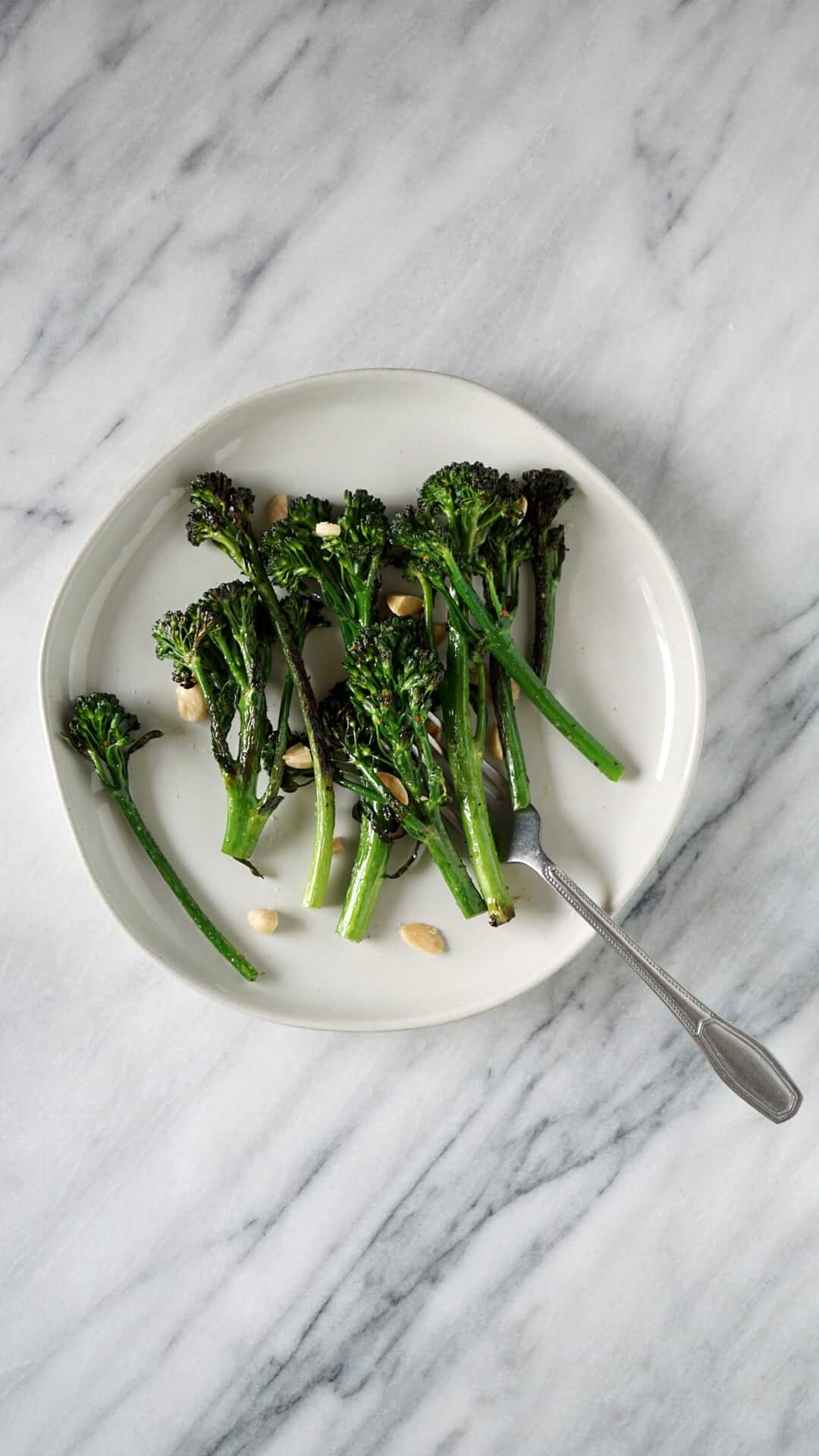 Broccolini on a white plate with a fork