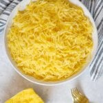 Spaghetti squash in a white bowl with two gold forks