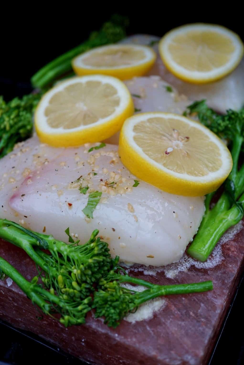 Halibut and broccolini on a salt block with lemons