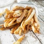 Air fryer french fries spilling out of a basket with ketchup