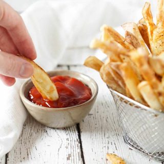 french fry dipped in ketchup and fries in a basket