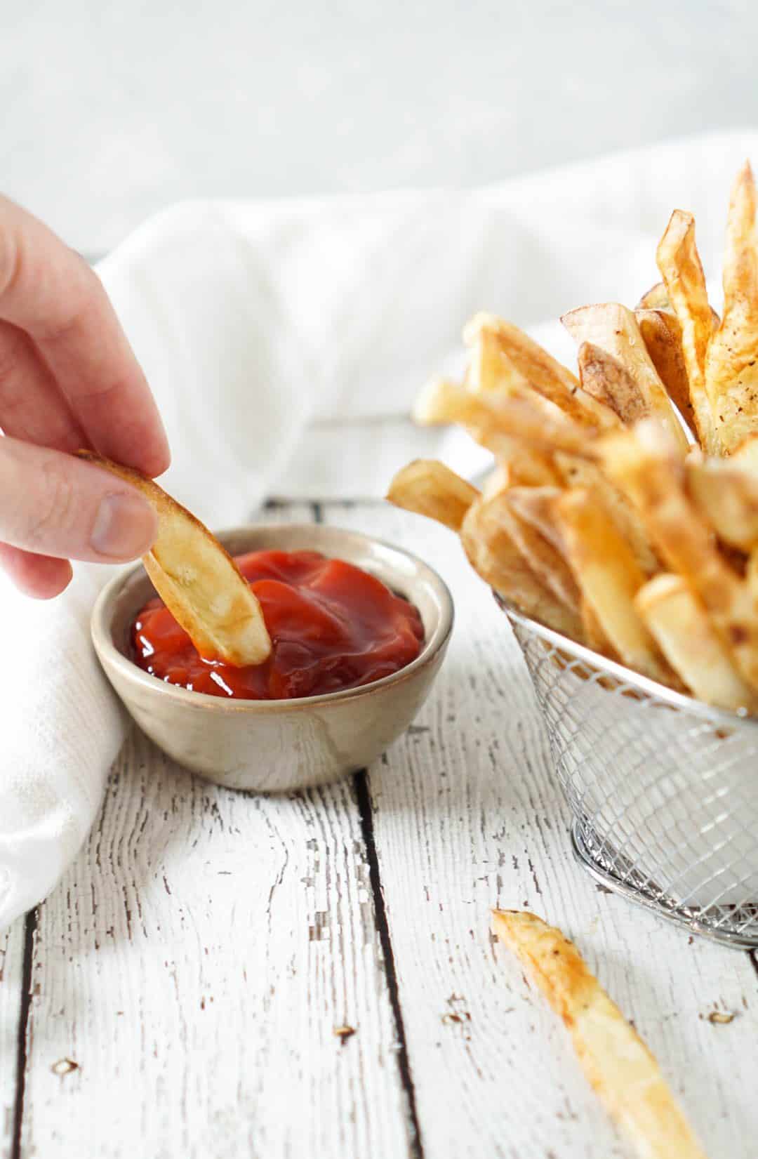 french fry dipped in ketchup and fries in a basket