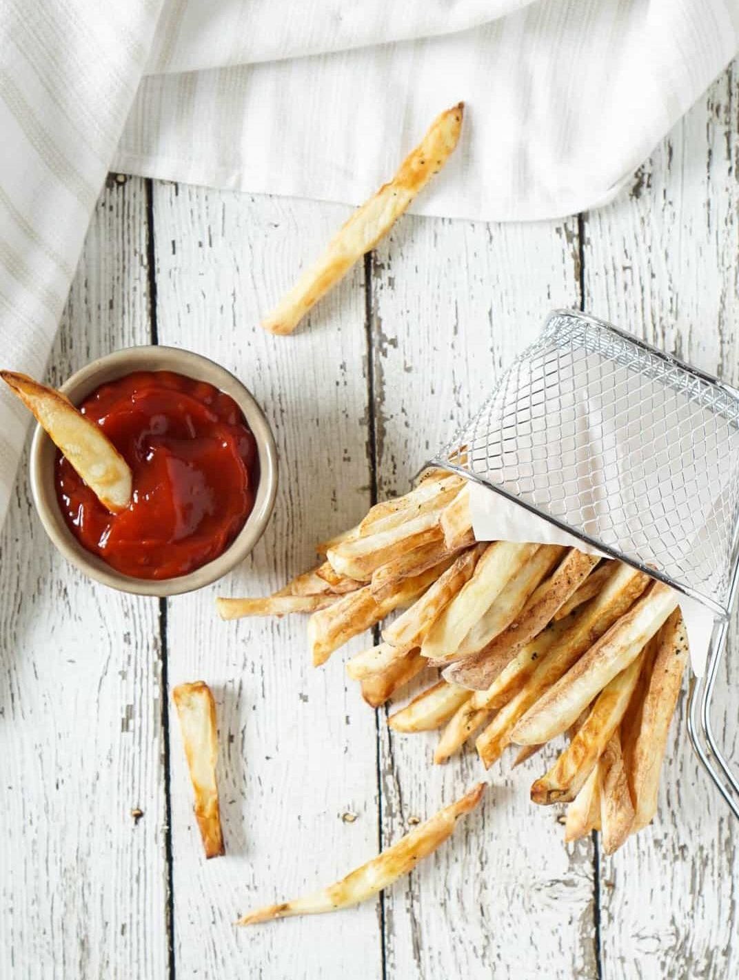 french fries spilling out of a basket with ketchup