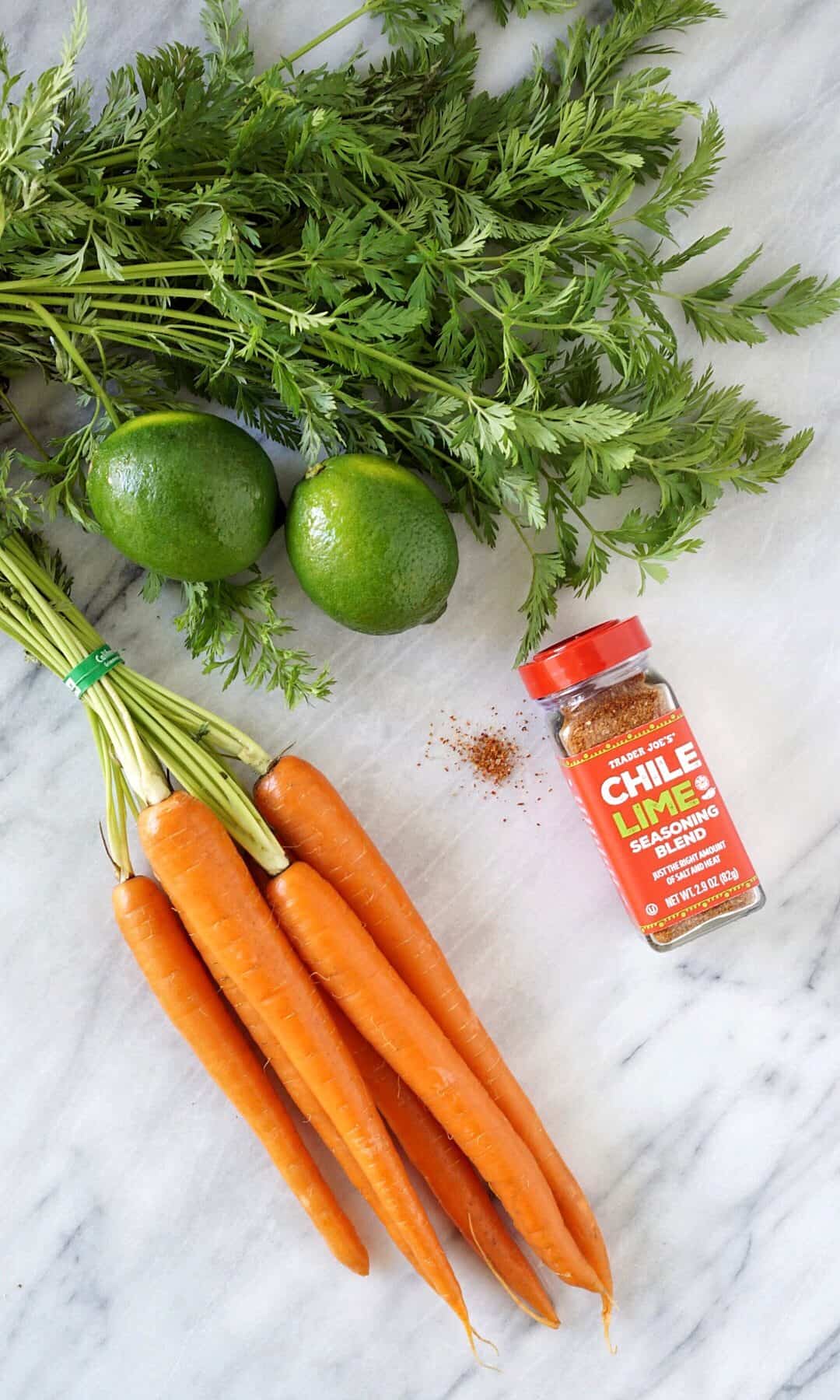 Carrots, limes, and seasoning on a marble board