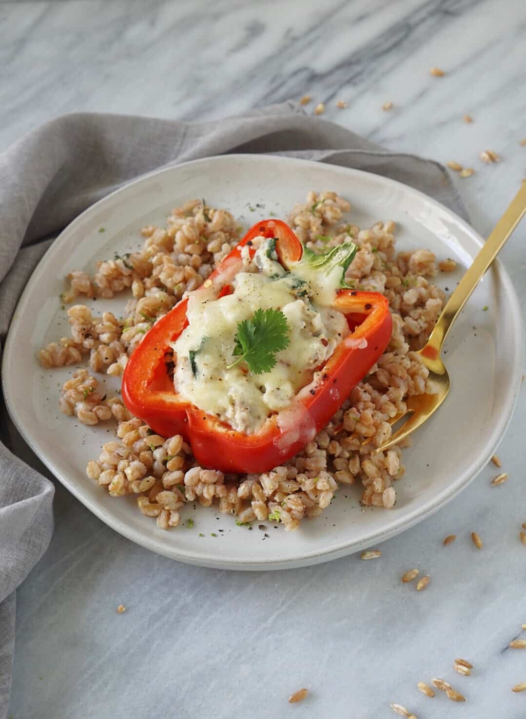 Stuffed pepper over farro on a white plate