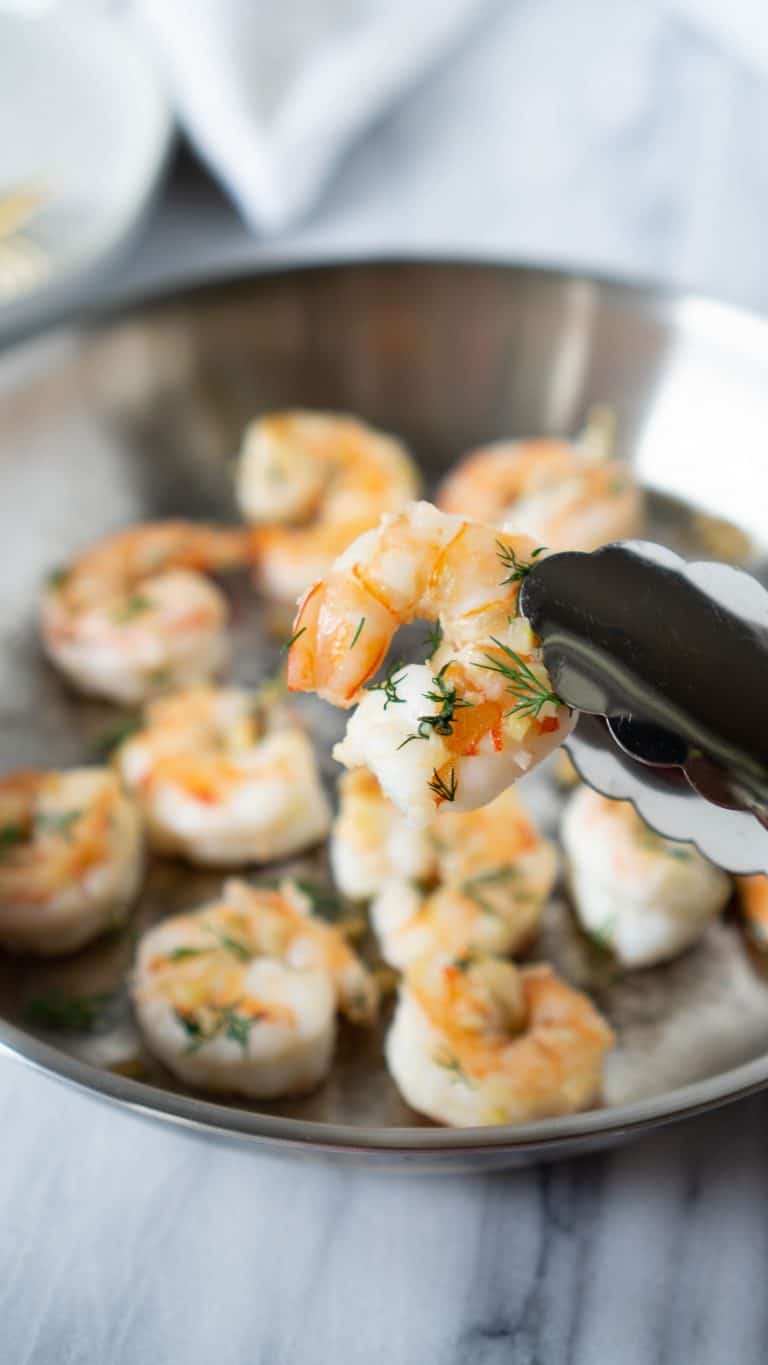 tongs holding garlic butter shrimp