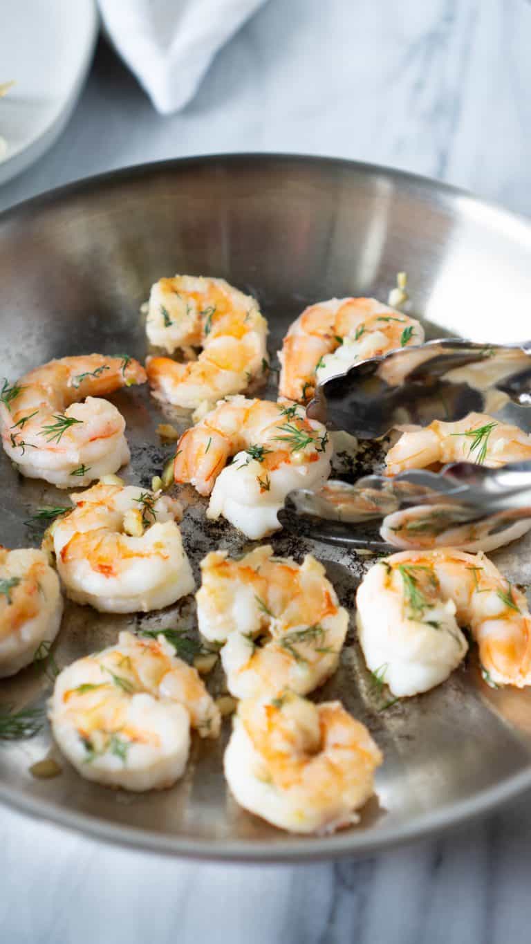 shrimp in a pan with tongs