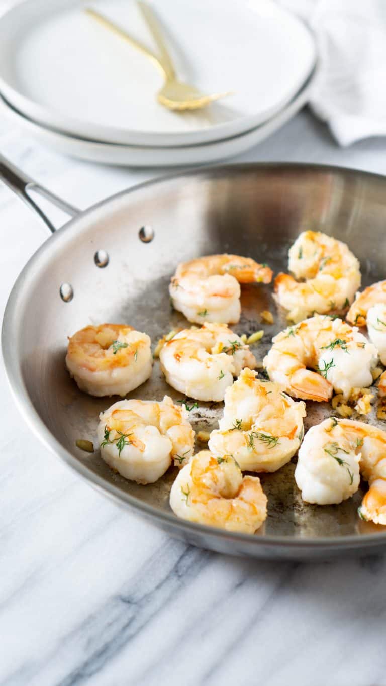 shrimp in a pan with two white plates