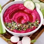 Roasted beet hummus in a bowl with vegetables on a tray