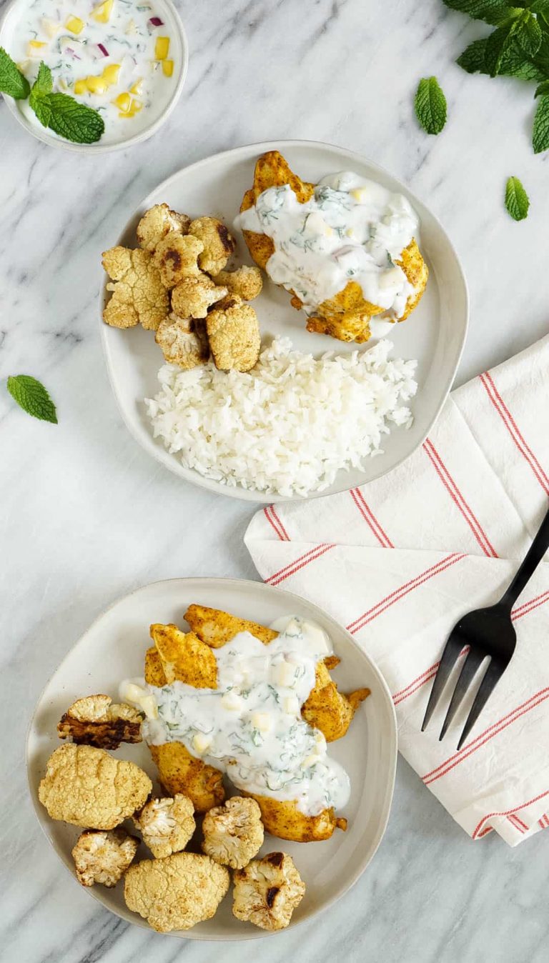 two plates of tandoori chicken with cauliflower and rice