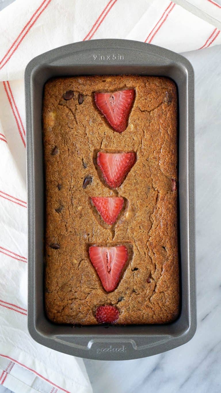 banana bread in a loaf pan with strawberries on top
