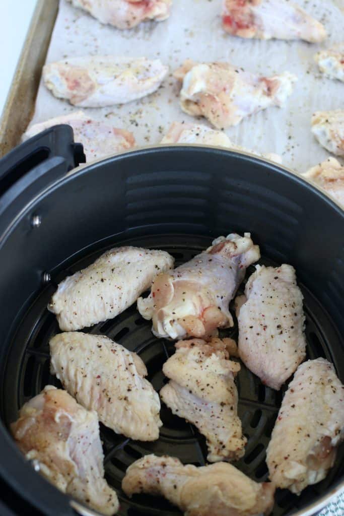 Chicken wing sections seasoned with salt, pepper and garlic powder in an air-fryer cooking basket.