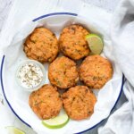 salmon cakes on a white plate with limes