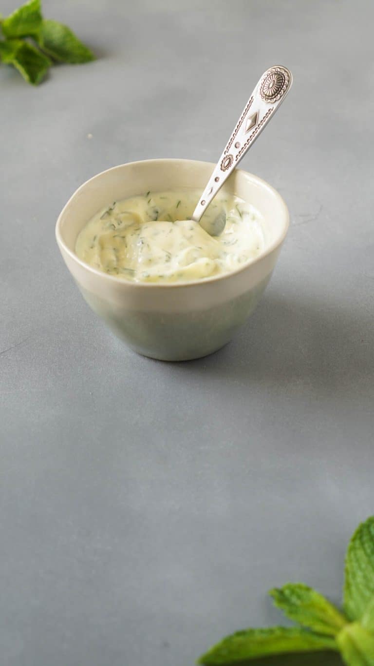 mayonnaise, dill, and mint in a small bowl with a silver spoon
