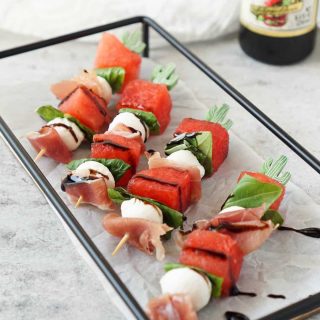 caprese skewers on a black tray with filippo berio balsamic glaze