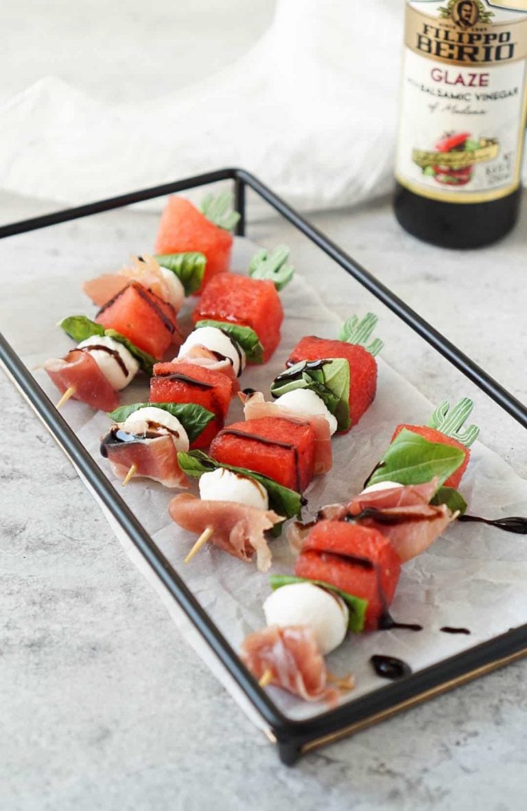 caprese skewers on a black tray with filippo berio balsamic glaze