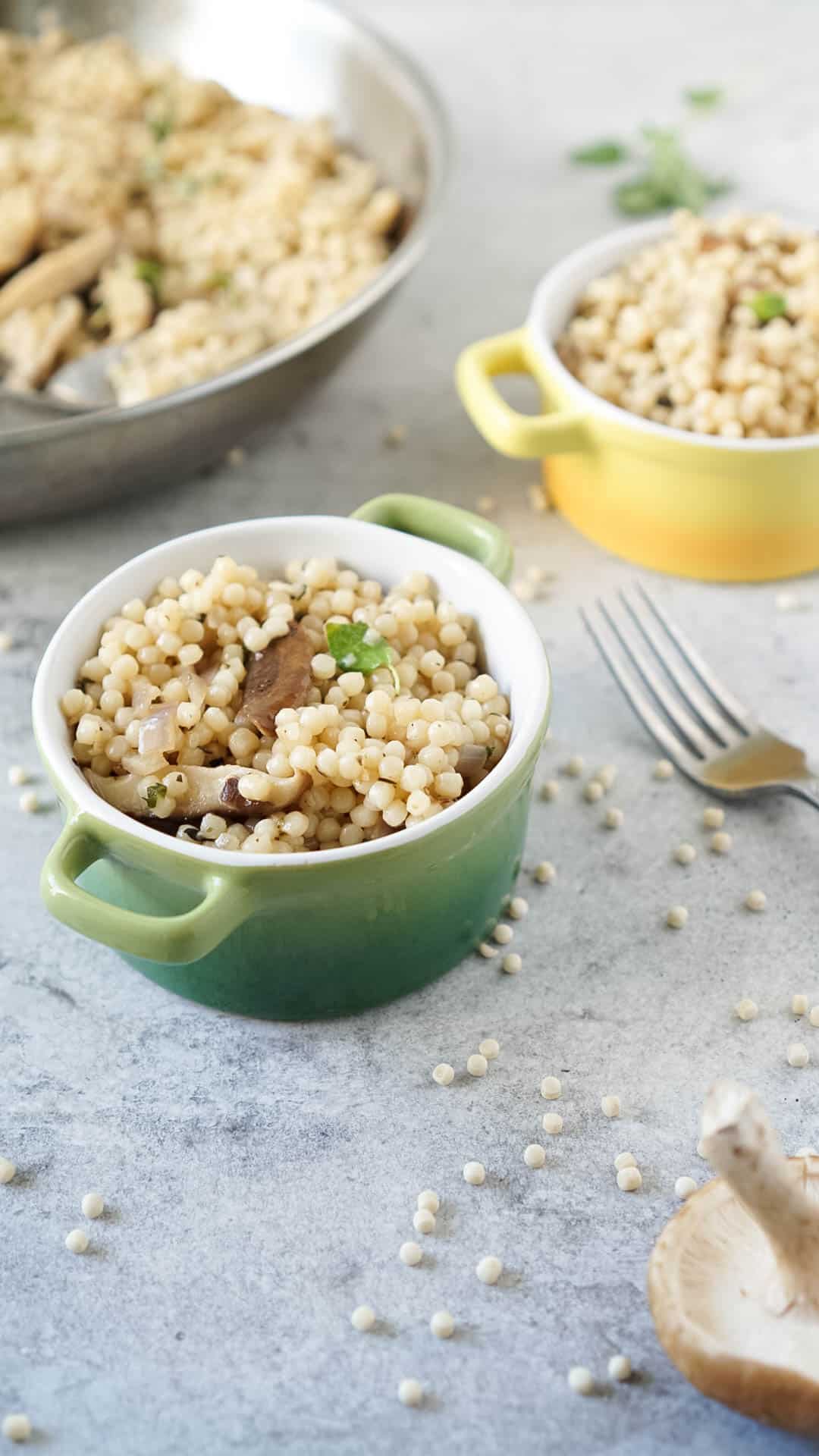 israeli couscous recipe in two colored bowls with a fork