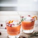 two Cranberry Orange Whiskey Cocktails on a wood table