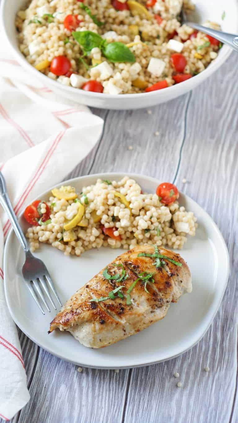 Grilled chicken on a white plate with couscous salad