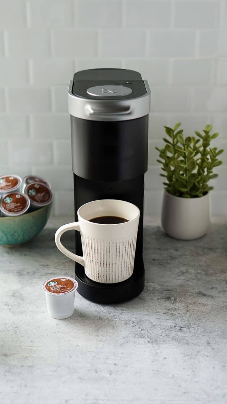 white coffee mug with k-cup pods and a black keurig