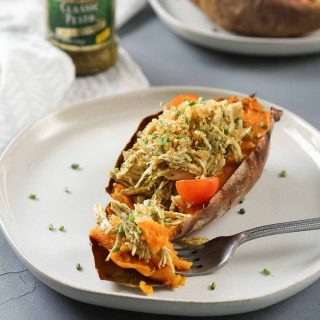 stuffed sweet potato on a white plate with a fork